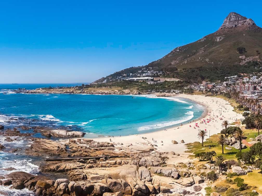 Camps Bay and beach and rocky coastline with restaurants and bars, a popular travel destination in Cape Town.