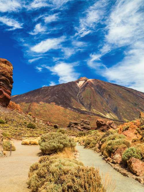 Panoramic view of unique Roque Cinchado unique rock formation with famous Pico del Teide mountain volcano summit in the background on a sunny day, Teide National Park, Tenerife, Canary Islands, Spain