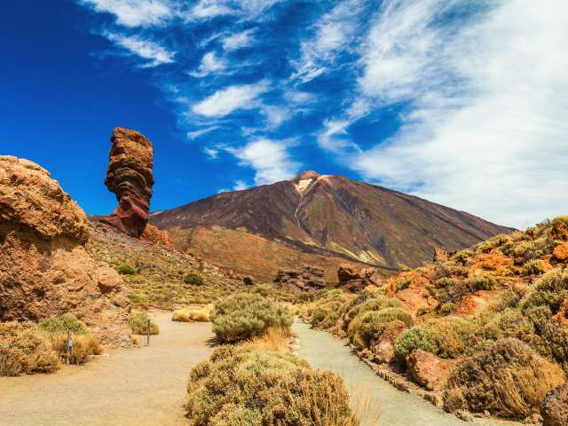 Panoramic view of unique Roque Cinchado unique rock formation with famous Pico del Teide mountain volcano summit in the background on a sunny day, Teide National Park, Tenerife, Canary Islands, Spain
