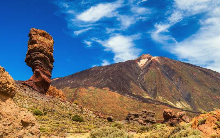 Panoramic view of unique Roque Cinchado unique rock formation with famous Pico del Teide mountain volcano summit in the background on a sunny day, Teide National Park, Tenerife, Canary Islands, Spain