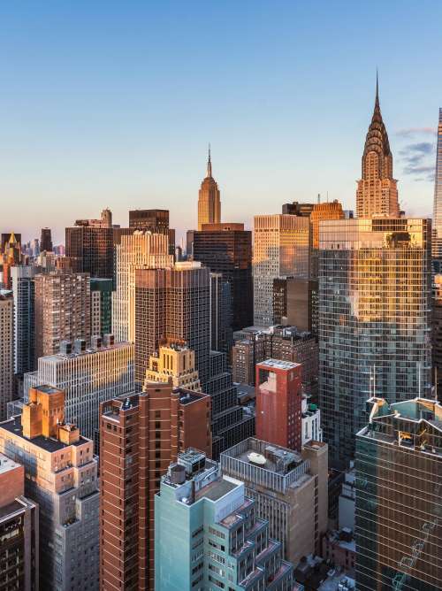 This high angle sunrise view from UN Plaza on the east side of Manhattan looks southwest over the Kips Bay neighborhood toward the Empire State Building, the Chrysler Building, and One Vanderbilt with Lower Manhattan and One World Trade Center in the distance.