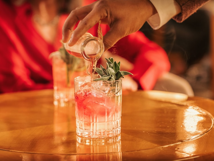 A bartender finishes off a fruity cocktail