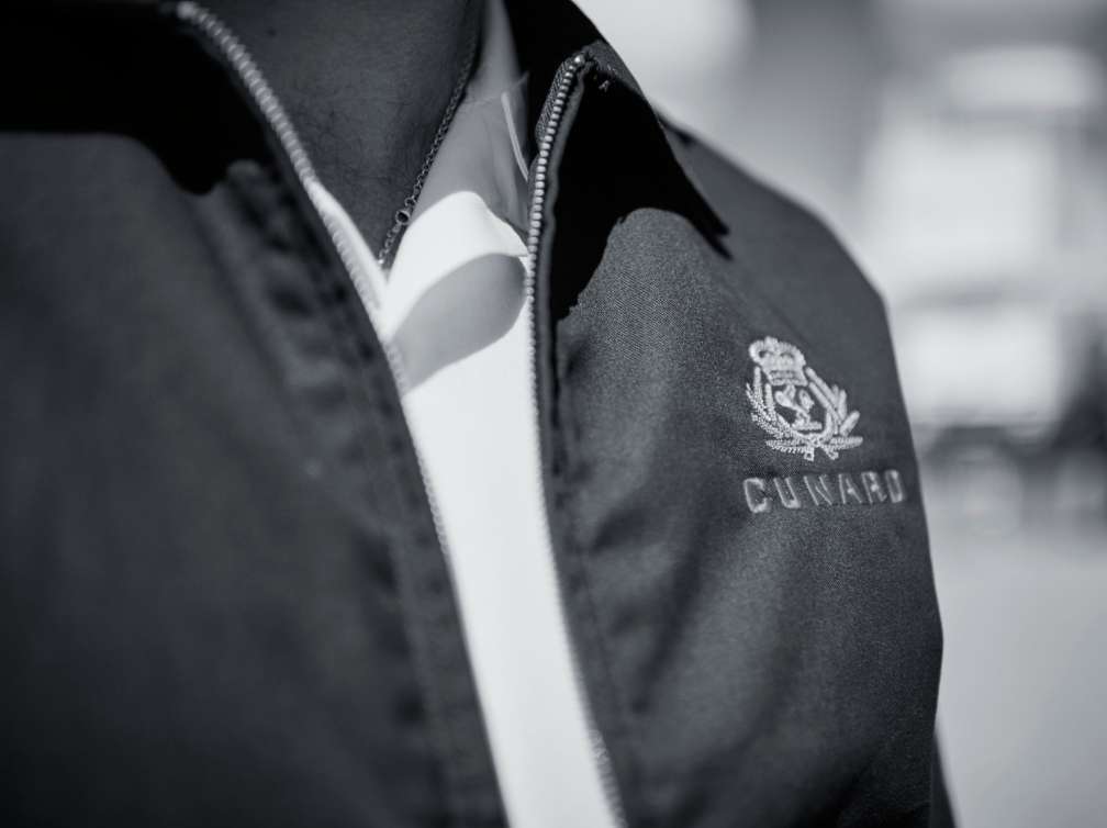 Close-up of Cunard logo embroidered on a jacket, featuring crown and laurel design