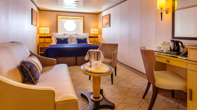 A typical oceanview Britannia stateroom on board Queen Mary 2, showing kingsize bed, living area and oceanview window
