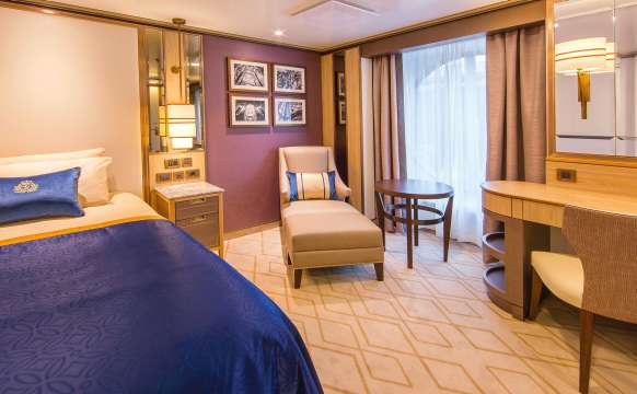 A typical single-occupancy oceanview Britannia stateroom on board Queen Mary 2, showing generous single bed, living area and oceanview window 