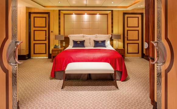 Bedroom of a Q2 Duplex Queens Grill Suite on board Queen Mary 2, showing double doors and kingsize bed