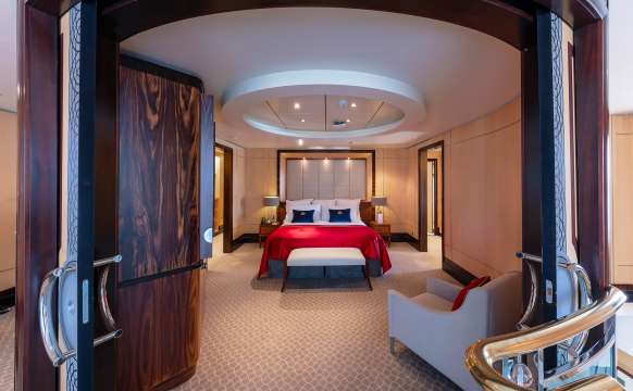 Bedroom on upper floor of a Q1 Grand Duplex Queens Grill Suite on Queen Mary 2, showing double doors and kingsize bed