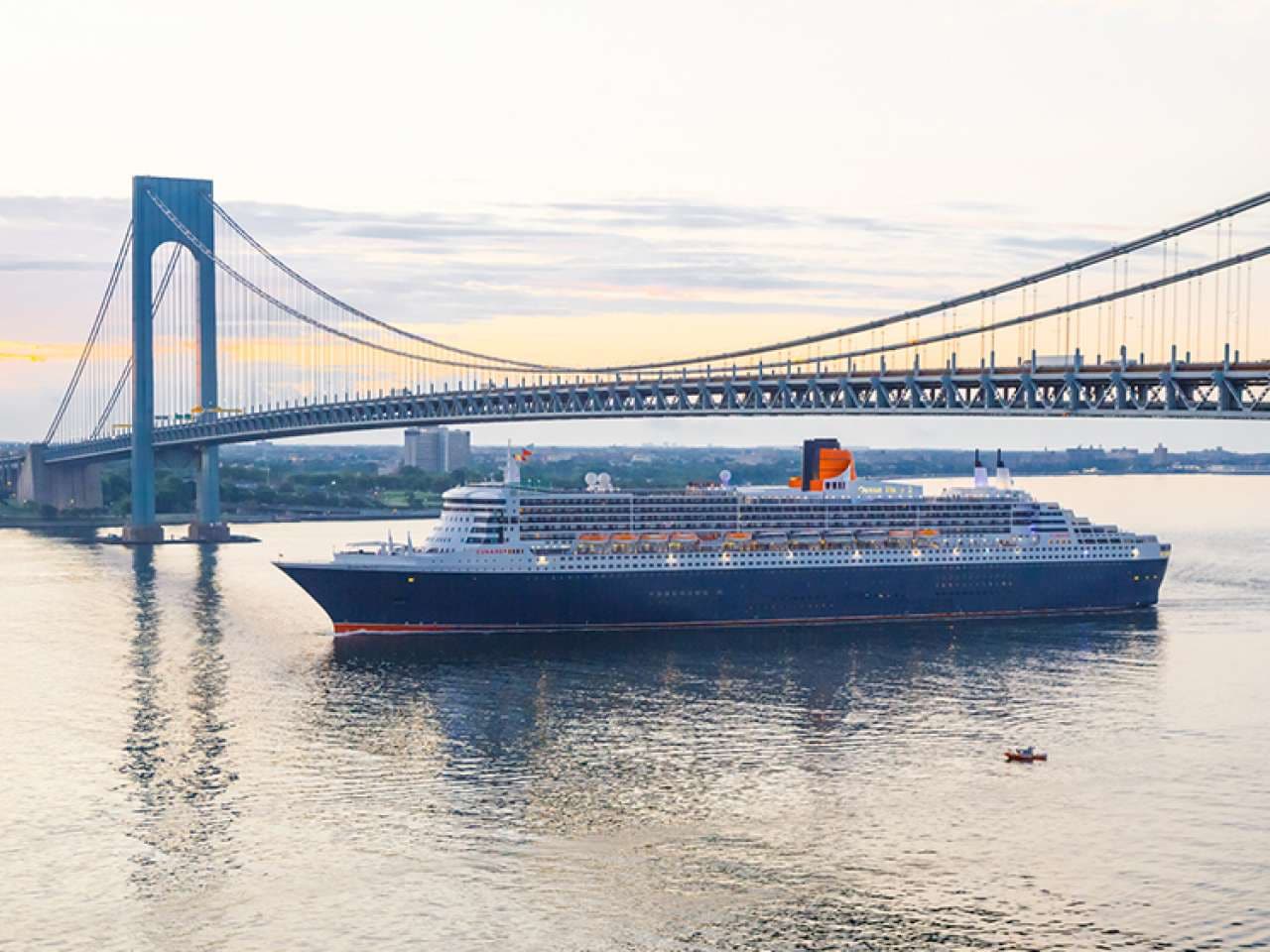 Cunard's Queen Mary 2 passing under a suspension bridge at dawn