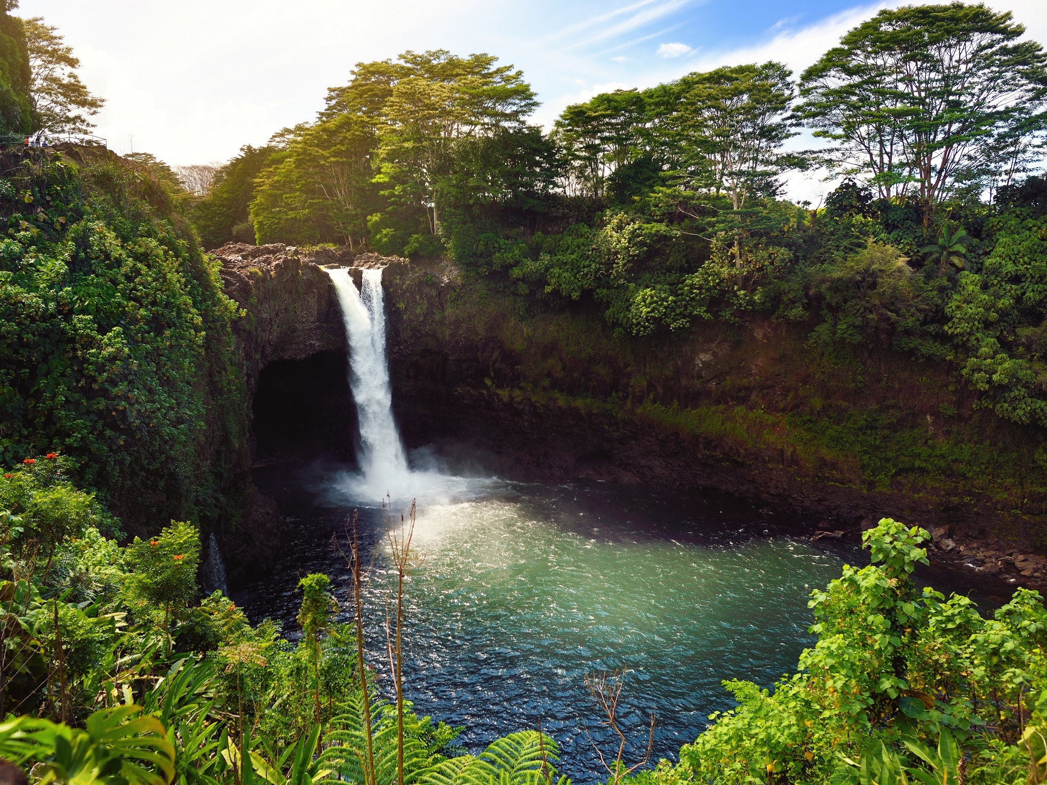 Majesitc Rainbow Falls waterfall in Hilo, Wailuku River State Park, Hawaii. The falls flows over a natural lava cave, the mythological home to Hina, an ancient Hawaiian goddess.