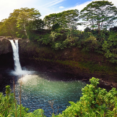 Majesitc Rainbow Falls waterfall in Hilo, Wailuku River State Park, Hawaii. The falls flows over a natural lava cave, the mythological home to Hina, an ancient Hawaiian goddess.