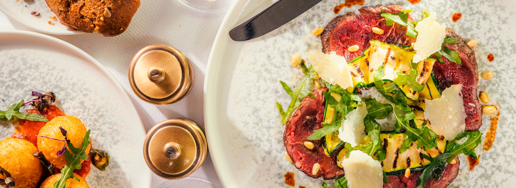 {"metadata_en_GB":{"alt-text":"Top-down view of a Cunard dining table, including golden salt and pepper mills, a beef entree, a tomato salad and freshly baked bread rolls, accompanied with white wine"},"metadata_en_AU":{"alt-text":"Top-down view of a Cunard dining table, including golden salt and pepper mills, a beef entree, a tomato salad and freshly baked bread rolls, accompanied with white wine"},"metadata_en_US":{"alt-text":"Top-down view of a Cunard dining table, including golden salt and pepper mills, a beef entree, a tomato salad and freshly baked bread rolls, accompanied with white wine"}}