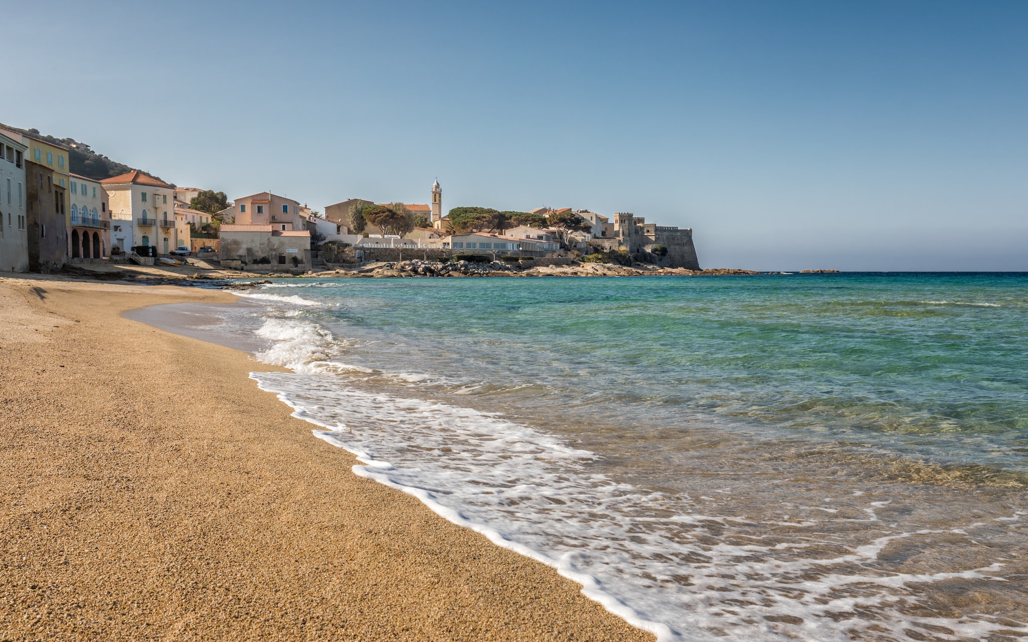 Turqouise Mediterranean sea lapping gently onto the golden sandy beach in front of the Balagne village of Algajola in Corsica; Shutterstock ID 582271594; Invoice Number: -