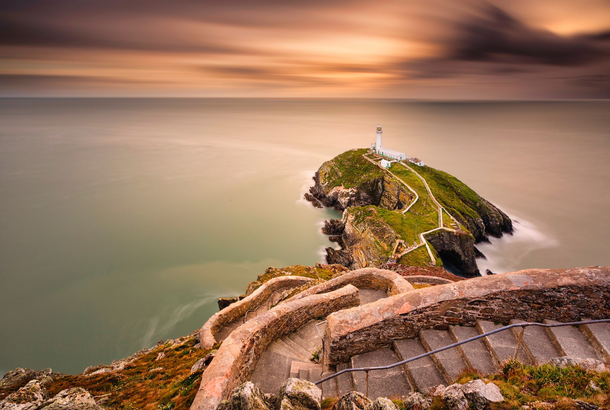 Lighthouse on coastal island with horizon and beautiful sunset at South Stack in Holyhead, North Wales. South Stack lighthouse at sunset overlooking the Irish Sea Isle of Anglesey