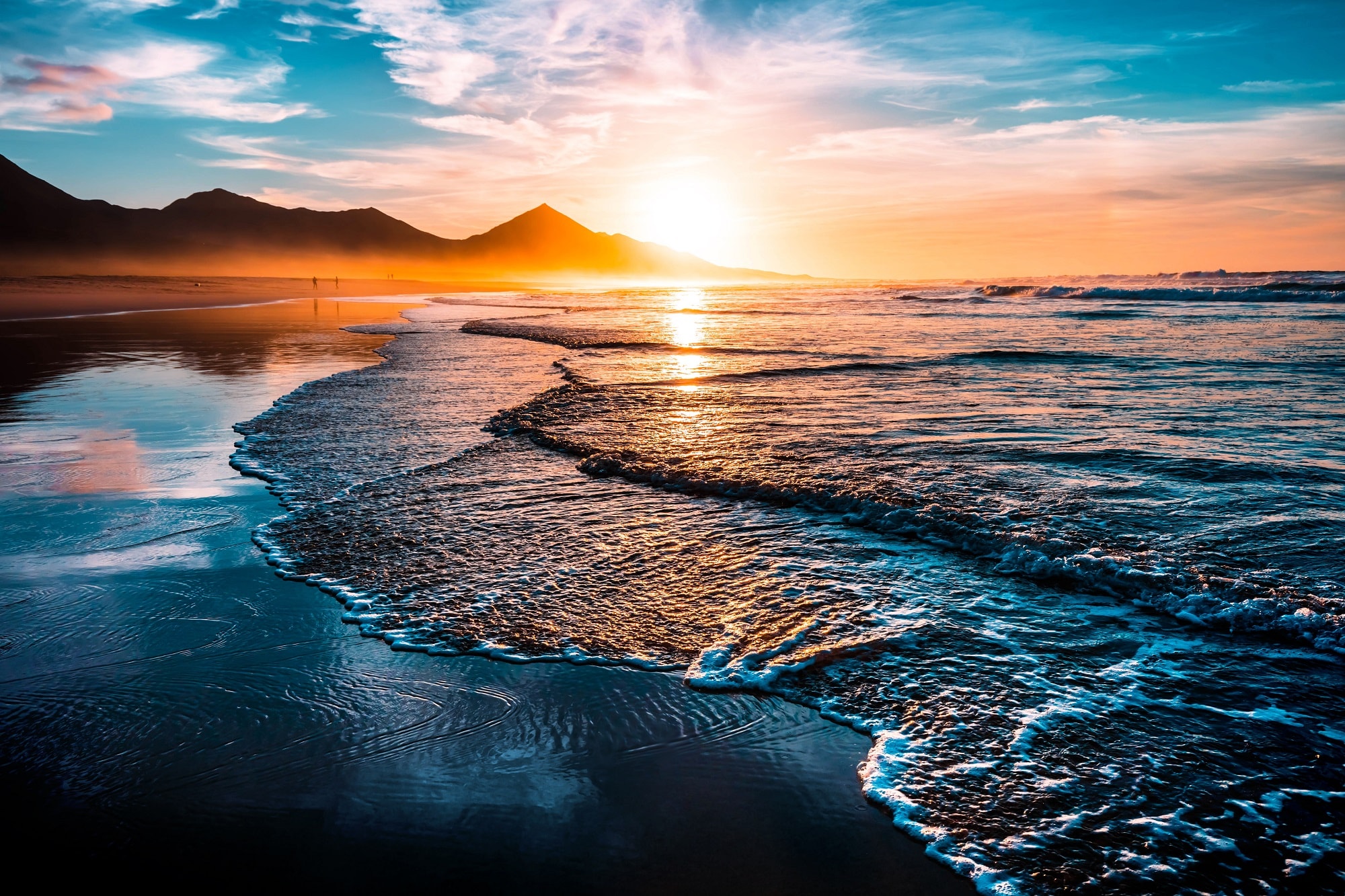 Amazing beach sunset with endless horizon and lonely figures in the distance, and incredible foamy waves. Volcanic hills in the background.; Shutterstock ID 746217742; purchase_order: n/a; job: Waves; client: cunard_digital; other: 