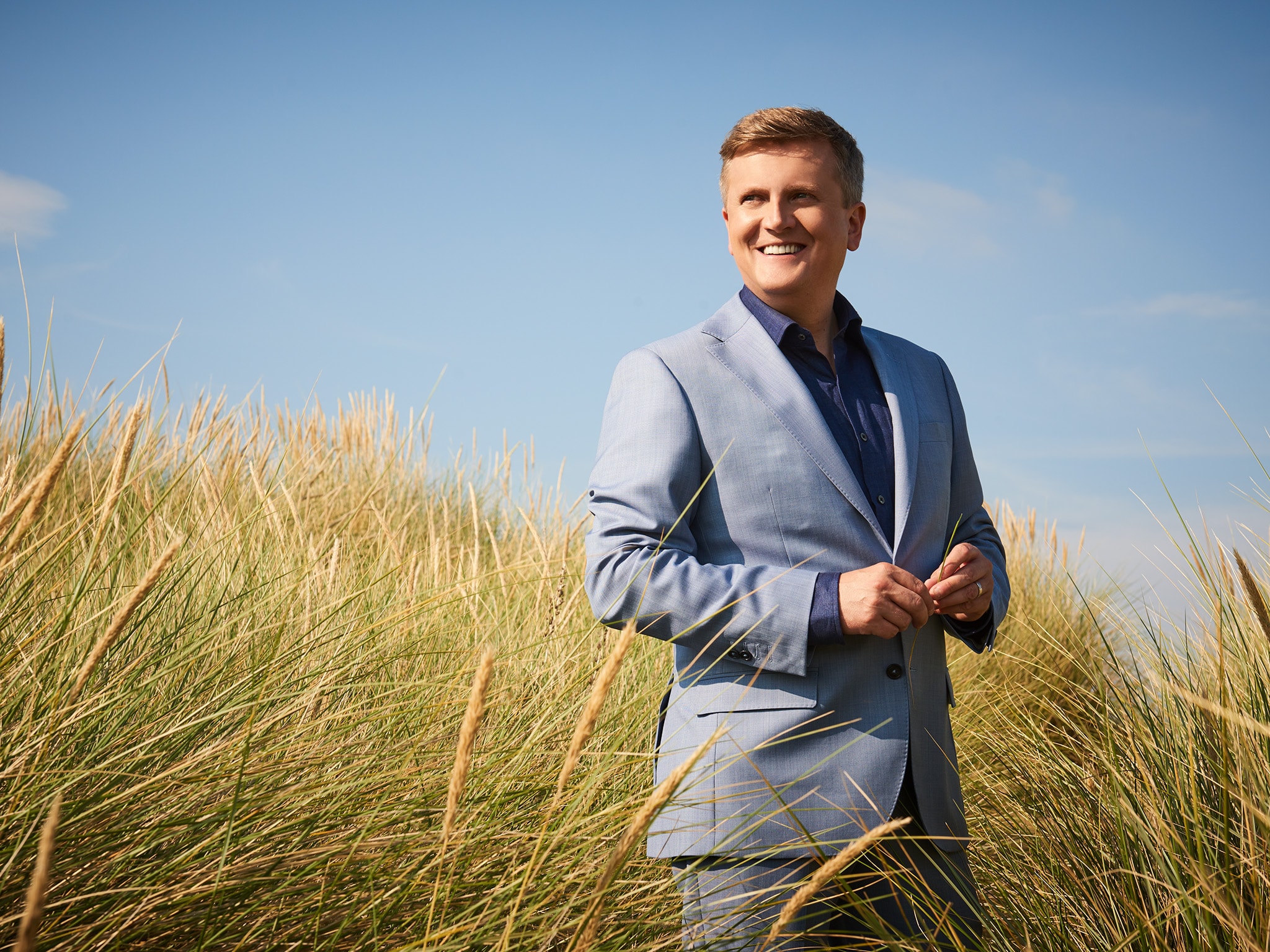 Singer Aled Jones staring wistfully into the distance in a wheat field on a glorious summer's day