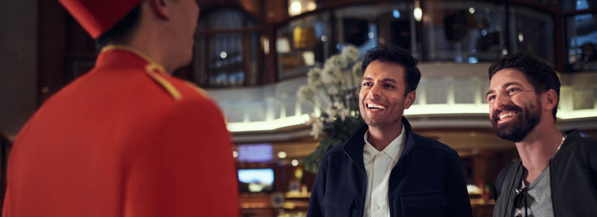 {"metadata_en_GB":{"alt-text":"Guests talking to a bellhop on board Queen Elizabeth"},"metadata_en_AU":{"alt-text":"Guests talking to a bellhop on board Queen Elizabeth"},"metadata_en_US":{"alt-text":"Guests talking to a bellhop on board Queen Elizabeth"}}