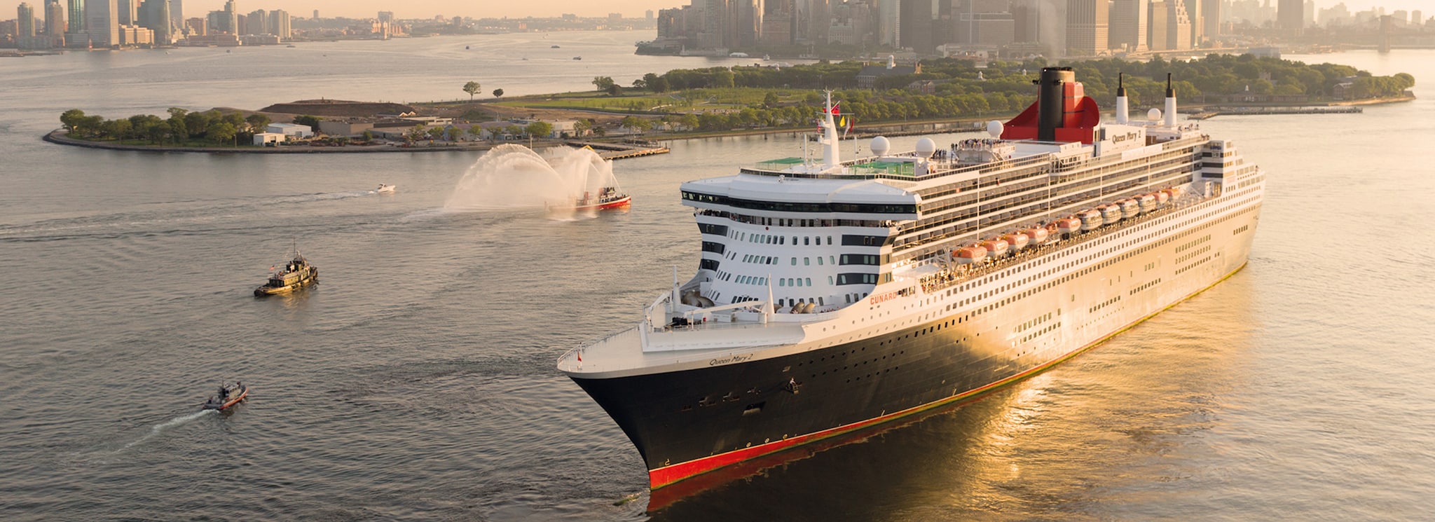 Brand shot of QM2 sailing out of New York at sunset